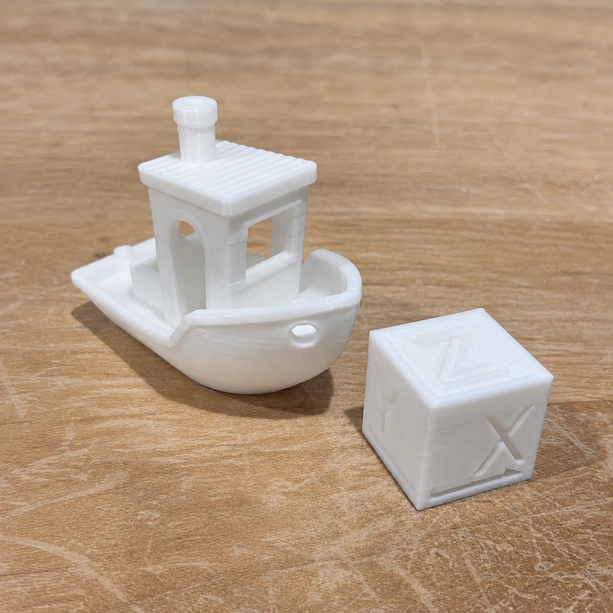 White Benchy boat and XYZ calibration cube on the shop’s wooden workbench