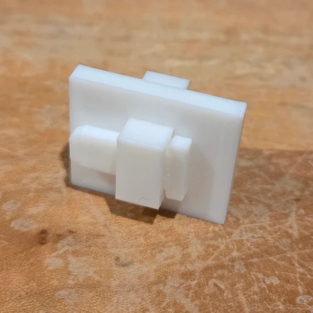 A white printed fitting on the workbench; the demonstration shows it sliding into place