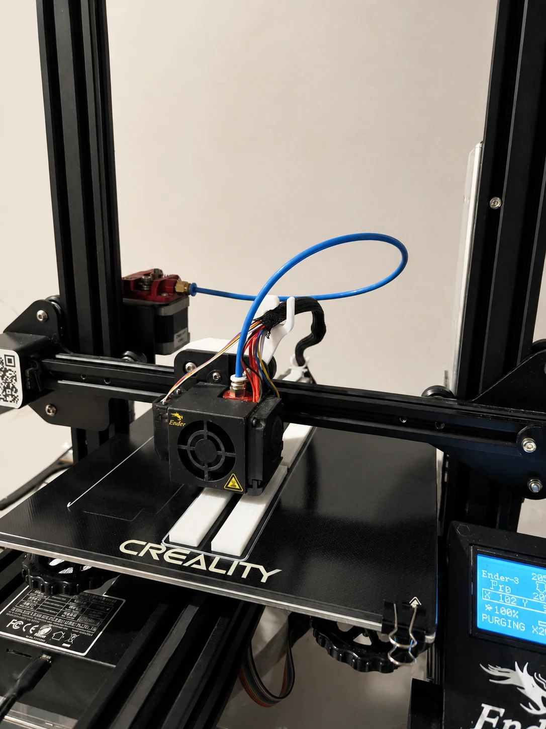 Real shop photograph of a desktop FDM printer making white parts